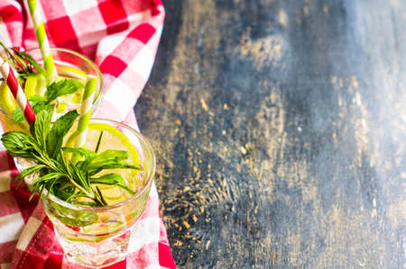Summer drink with ice, mint, rosemary and lime on rustic table