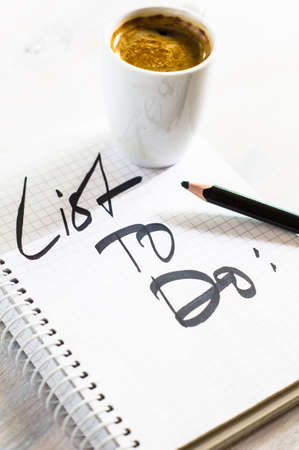 Notebook with List to do on wooden desk with cup of coffeeの写真素材