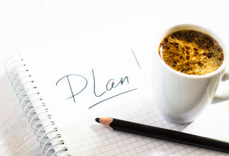 Notebook with an action plan  on wooden desk with cup of coffeeの写真素材