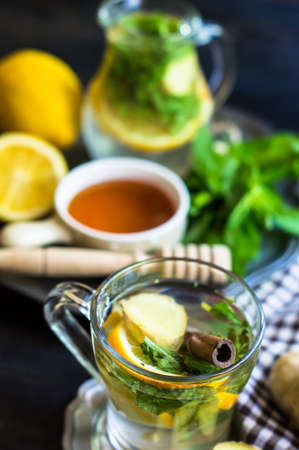 Cup of tea with ginger, mint, lemon, cinnamon sticks and anise star spice on the rustic backgroundの写真素材