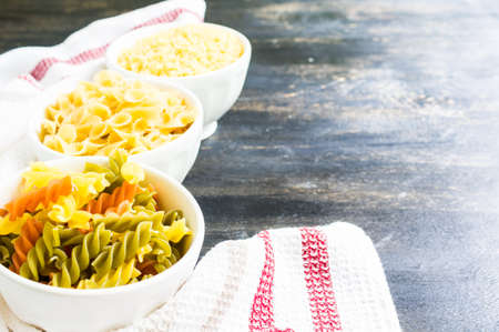 Pasta cooking concept with  basil, tomatoes,  pepper chili, garlic and pasta on vintage wooden backgroundの写真素材