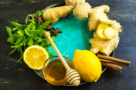 Cup of tea with ginger, mint, lemon, cinnamon sticks and anise star spice on the rustic backgroundの写真素材