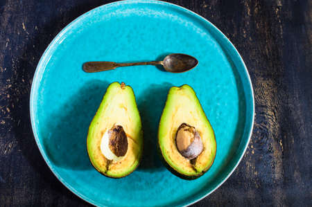 Fresh avocado vegetable on vintage style plate on rustic wooden tableの写真素材