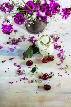 Fresh organic cherries and wild summertime flowers on rustic wooden tableの写真素材