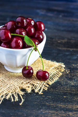 Fresh cherry berries on rustic wooden table and vintage background