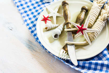 Marine table setting with sea stars and vintage tableware on rustic wooden background