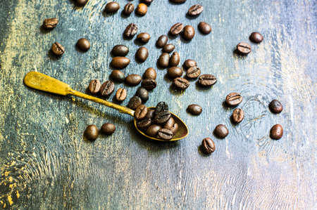 Spoon with coffee beans and spices like anise star on rustic wooden backgroundの写真素材
