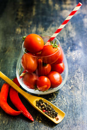 Cooking concept with fresh cherry toatoes, pepper grain, salt and straw on rustic wooden backgroundの写真素材
