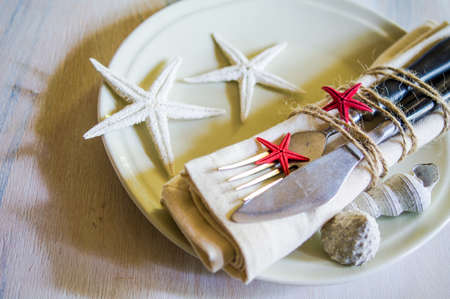 Marine table setting with sea stars and vintage tableware on rustic wooden backgroundの写真素材