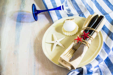 Marine table setting with sea stars and vintage tableware on rustic wooden backgroundの写真素材
