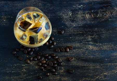 Glass of iced coffee with milk on rustic wooden backgroundの写真素材