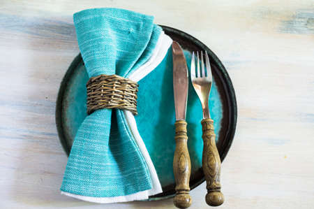 Summertime table setting with bright napkin and tableware on rustic wooden tableの写真素材