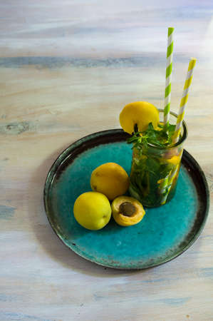 Summertime detox drink with fresh mint and apricot in the glass with bright straws on wooden rustic tableの写真素材