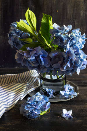 Vintage style table setting with fresh blue hydrangea flowers on rustic wooden table