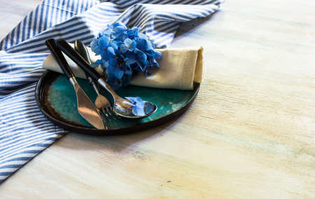 Vintage style table setting with fresh blue hydrangea flowers on rustic wooden tableの写真素材