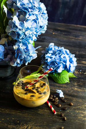 Glass of iced coffee with milk on rustic wooden backgroundの写真素材