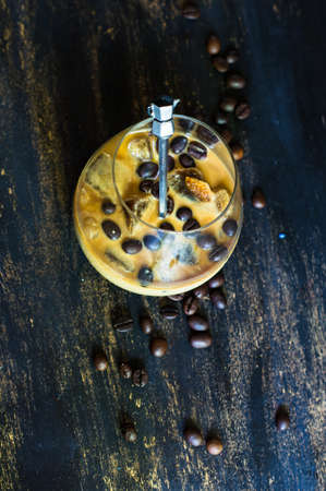 Glass of iced coffee with milk on rustic wooden backgroundの写真素材