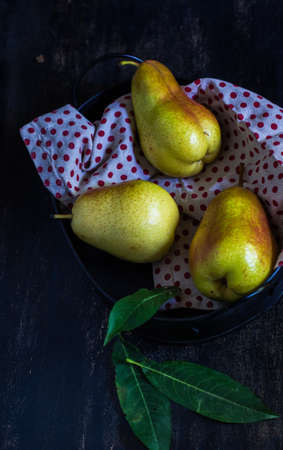 Fresh organic pears on vintage plate with rustic napkin on old wooden kitchen tableの写真素材