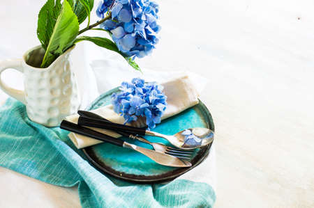 Vintage style table setting with fresh blue hydrangea flowers on rustic wooden tableの写真素材