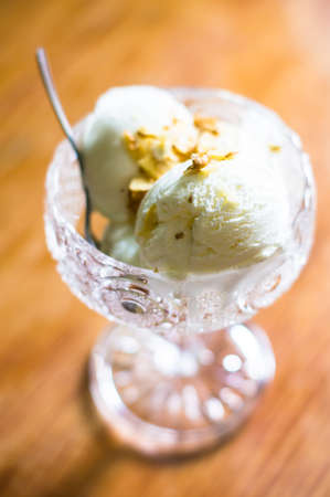 Ice cream in vintage bowl with nuts on russtic wooden tableの写真素材