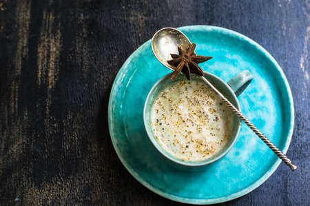Cup of cappuccino with anise star and cinnamon spice on rustic wooden tableの写真素材