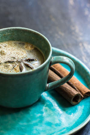 Cup of cappuccino with anise star and cinnamon spice on rustic wooden tableの写真素材
