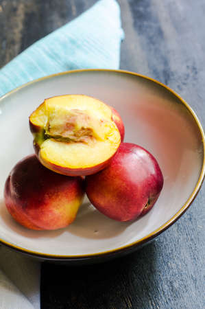 Fresh organic nectarine fruits in rustic style plates on old wooden tableの写真素材
