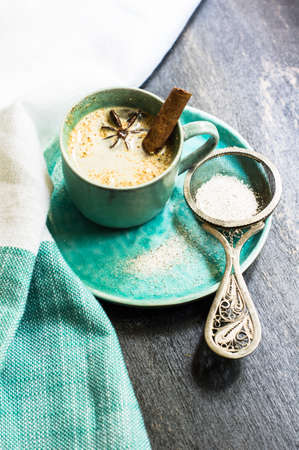 Cup of cappuccino with anise star and cinnamon spice on rustic wooden tableの写真素材