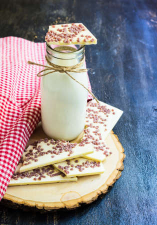 Vintage bottle of milk and white chocolate on rustic wooden table