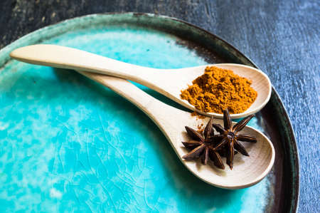 Wooden spoons with anice stars and cinnamon spice on rustic plateの写真素材