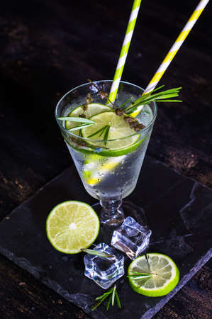 Detox beverage with fresh lime and rosemary on rustic background