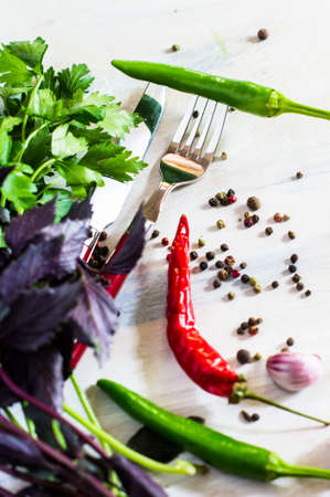 Cooking concept with fresh and organic vegetables like a chili peppers, parsley, garlic and pepper grain on rustic wooden tableの写真素材