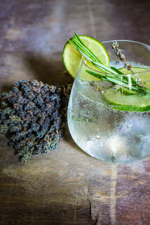 Detox beverage with fresh lime and rosemary on rustic background