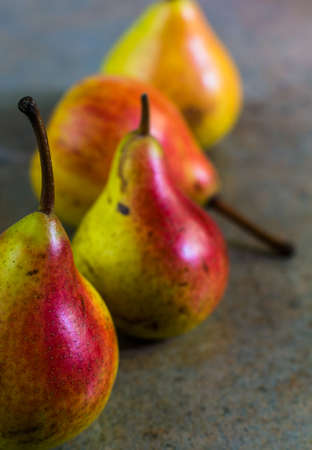 ripe pear with red side on rustic stone table
