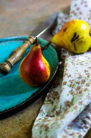 ripe pear with red side on rustic stone table