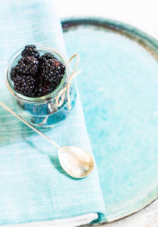 Ripe blackberry fruits in vintage bowl on rustic wooden table