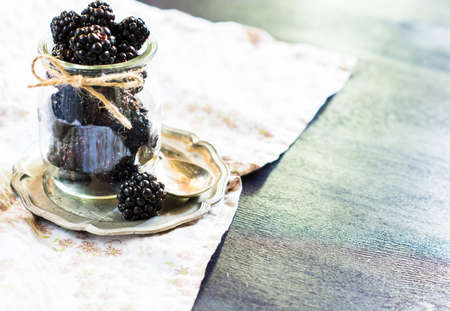 Ripe blackberry fruits in vintage bowl on rustic wooden table