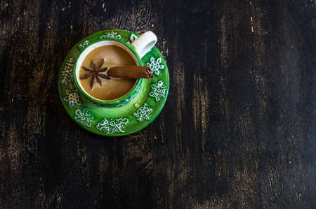 Cup of Christmas cappuccino with spices like anise star and cinnamon stick on holiday backgroundの写真素材