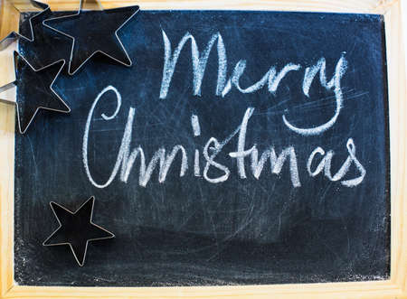 Merry Christmas written with chalk on a chalkboard with traditional christmas decorations