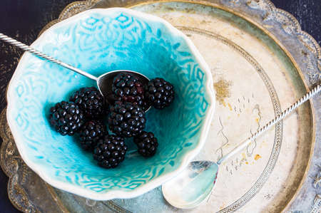 Ripe blackberry fruits in vintage bowl on rustic wooden table