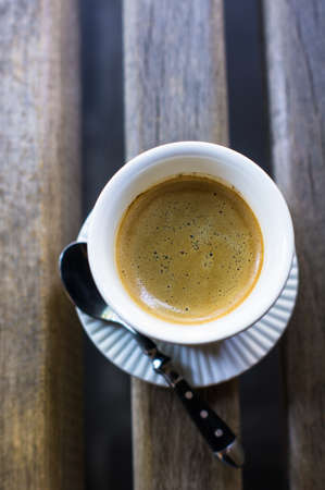 Black and white cup of coffee on rustic outdoor tableの写真素材