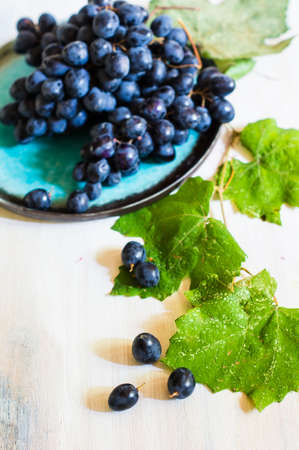 Fresh organic autumnal fruits and rustic plates on old wooden tableの写真素材