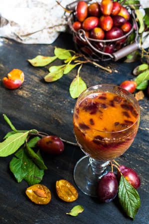 Glass of plum's smoothie and fresh organic plums on rustic tableの写真素材