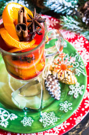 Mulled wine in a glass and christmas time decorations on rustic wooden tableの写真素材