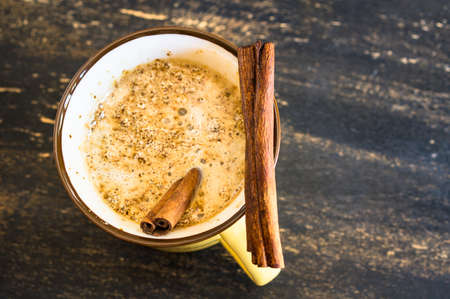 Vintage cup of coffee with milk with christmas time spices on rustic table