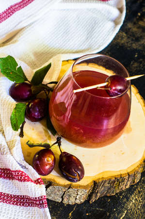 Glass of plum's smoothie and fresh organic plums on rustic tableの写真素材