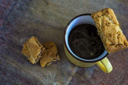 Cup of coffee and fruit mini cakes on wooden tableの写真素材