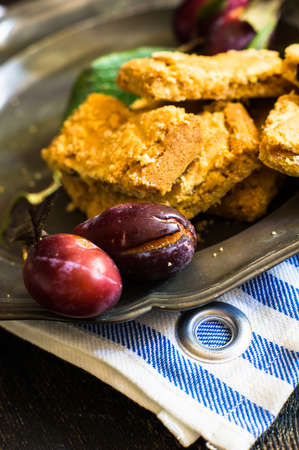 Plum cake and fresh plums with glass of juice on rustic tableの写真素材