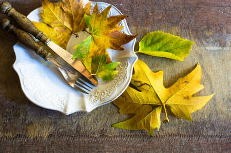Autumnal table setting with bright yellow male leaves on wooden rustic tableの写真素材