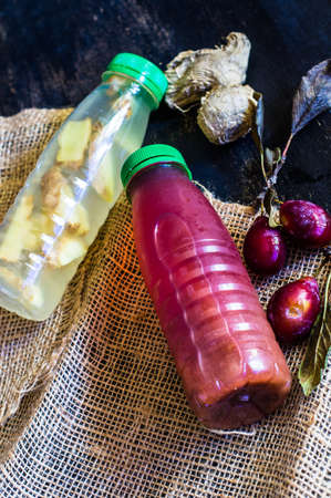 Bottle with detox drinks with plums and ginger on dark wooden tableの写真素材